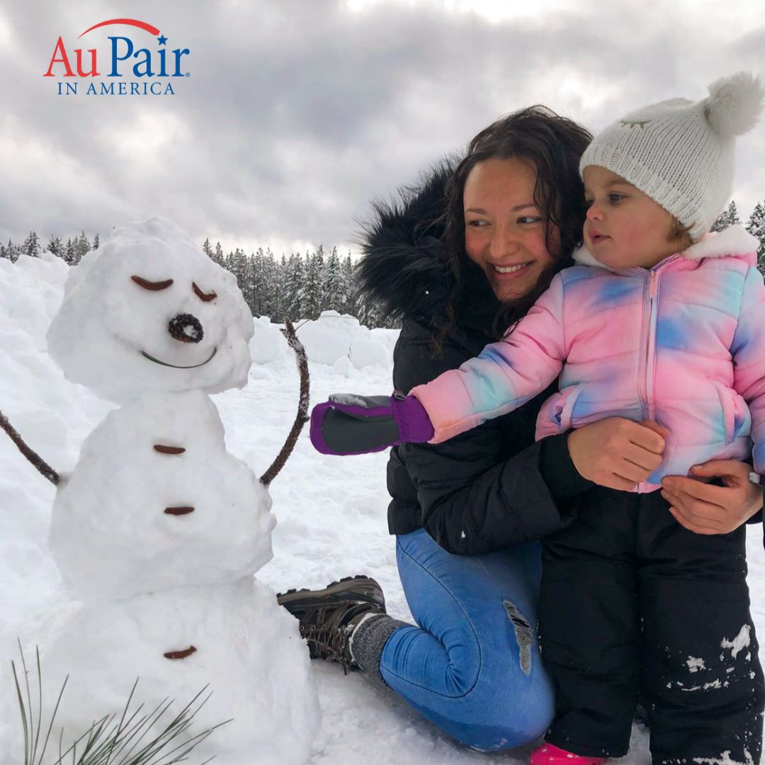 au pair and child building a snowman