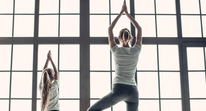 mom doing yoga pose with daughter