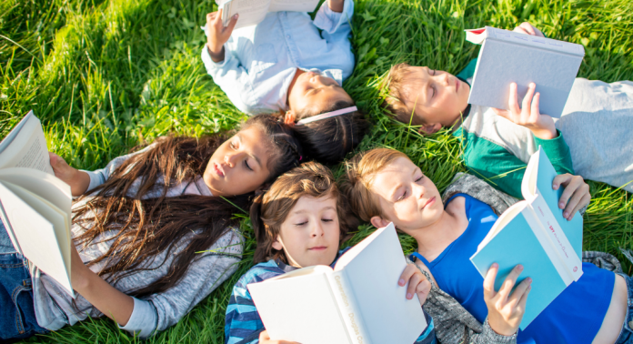 kids reading books in grass