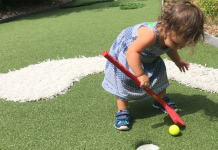 little girl playing mini golf