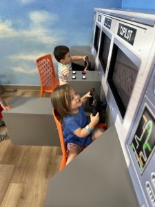 Children operate flight simulator at The Kids Landing indoor play space. 